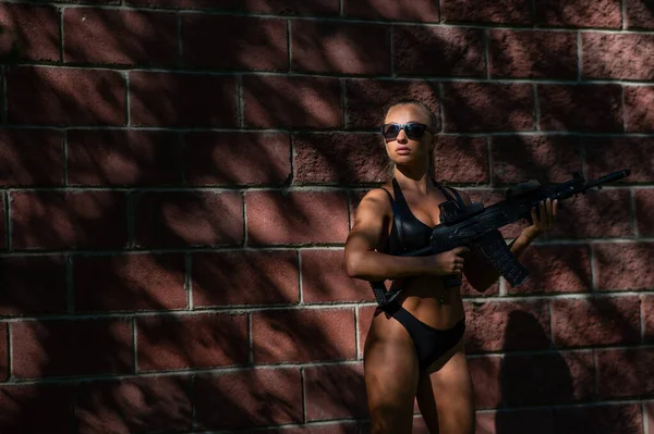 Een Blanke Vrouw Bikini Houdt Een Machinegeweer Tegen Een Stenen — Stockfoto