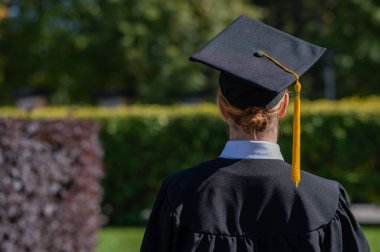 Bir kadın mezuniyet şapkasını mavi gökyüzüne fırlatıyor.