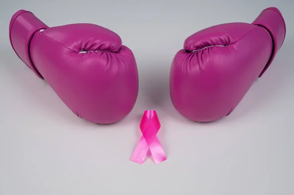 Pink boxing gloves and a pink silk ribbon on a white background. Breast cancer concept