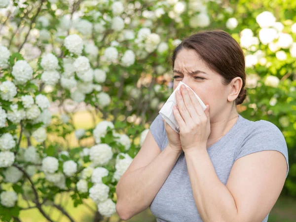 stock image Caucasian woman suffers from allergies and sneezes while walking in the park