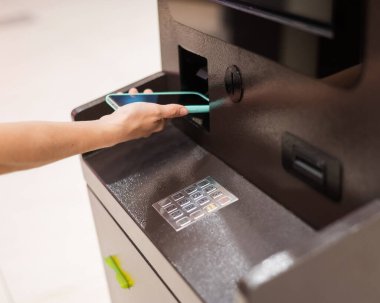 ATM 'de akıllı telefon kullanan bir kadın. NFC çevrimiçi bankacılık kavramı