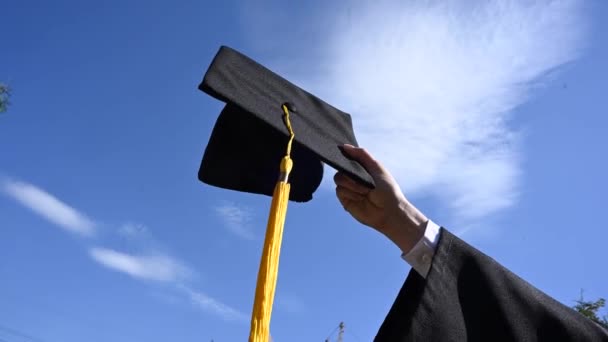 青い空に対して卒業キャップを持つ女性の手のクローズアップ — ストック動画