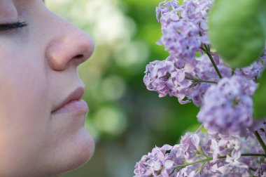 Beyaz kadın çiçek açan leylağı kokluyor. Bahar havası