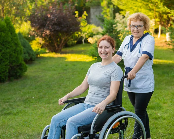 Elderly Female Nurse Walks Middle Aged Woman Wheelchair Park — Stockfoto