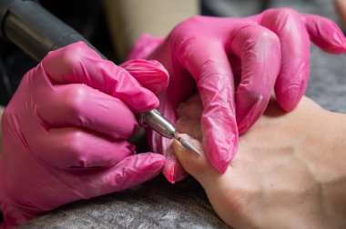 Usta müşteriye donanım pedikürü yapıyor. Kütikül tedavisi