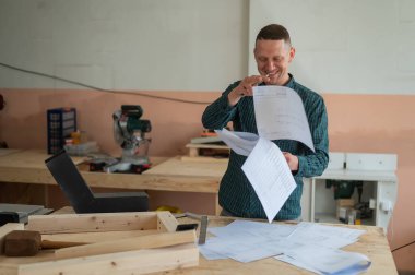 Caucasian man assembles furniture in the workshop and looks at the instructions