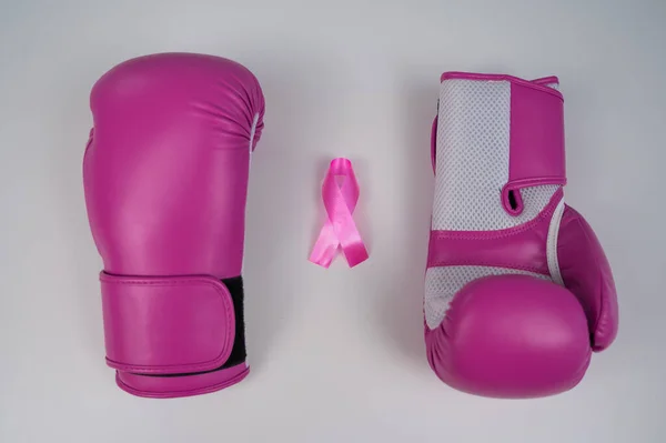 Pink boxing gloves and a pink silk ribbon on a white background. Breast cancer concept