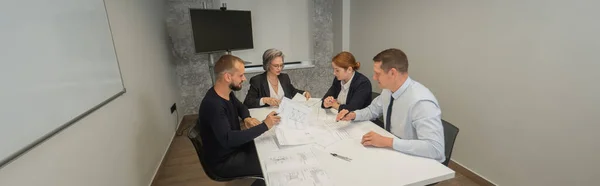 Four Business People Sitting Table Discussing Blueprints Designers Engineers Meeting — Stock Photo, Image