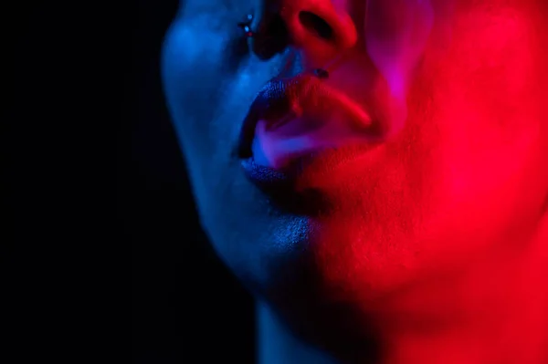 Asian woman with short haircut smoking in neon light. close-up portrait