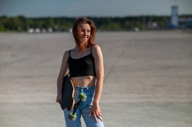 Beyaz bir kadın uzun bir sörf tahtası tutuyor.