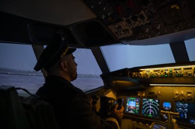 Bir adam uçak simülatöründe pilot olmak için okuyor.