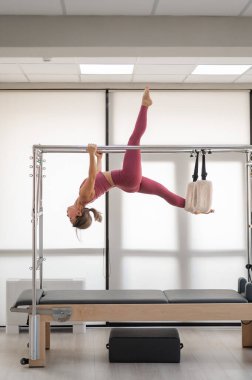 Pembe spor kıyafetli güzel Asyalı kadın yatakta pilates yapıyor.