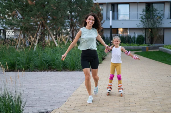 Mother helps daughter learn to roller skate