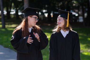Balo elbiseli iki mutlu kız öğrenci açık havada