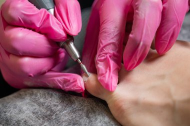 Usta müşteriye donanım pedikürü yapıyor. Kütikül tedavisi