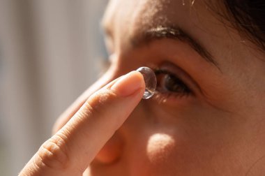 Close-up portrait caucasian woman putting on a contact lens