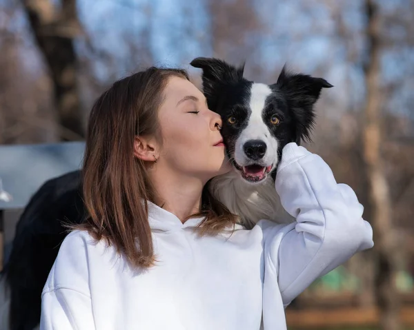 白人女性抱擁彼女の犬ボーダーコリーながら 秋の公園のベンチに座って — ストック写真
