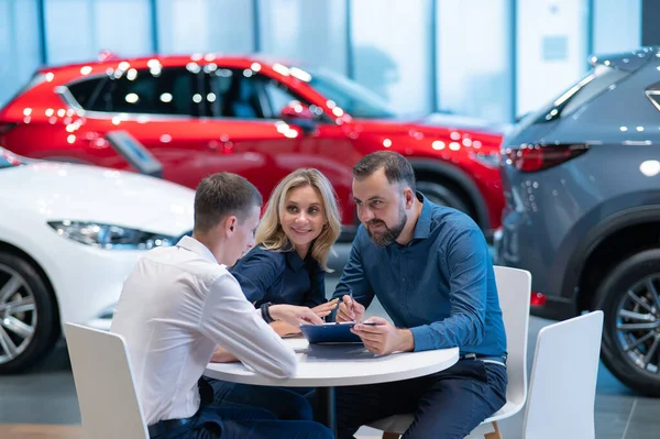 stock image Happy caucasian couple signs a contract for the purchase of a car salon