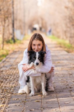 Sonbahar parkında sınır köpeğini kucaklayan beyaz bir kadın. Köpekli bir kızın portresi.