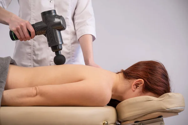 Medico Che Massaggia Schiena Una Paziente Con Una Pistola Massaggiatrice — Foto Stock