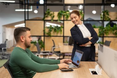 Masaüstünde duran kızıl saçlı beyaz kadın ve sakallı adam. Meslektaşlar iş tartışıyor