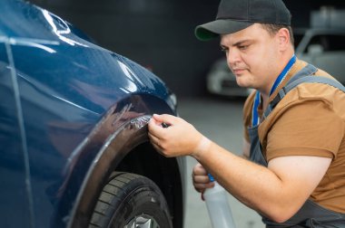 Araba servisindeki usta koruyucu kesiciyi kesiyor.