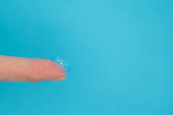 stock image Woman holding contact lens on blue background