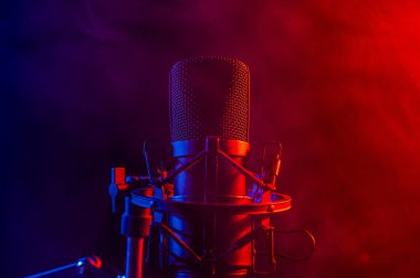 Siyah arka planda pembe dumanlı profesyonel mikrofon.