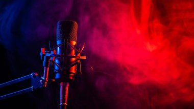 Siyah arka planda pembe dumanlı profesyonel mikrofon.