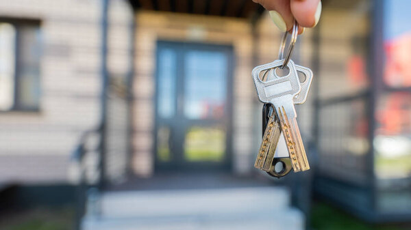 A woman holds the keys to a new house. Close-up of a female hand. Buying a property