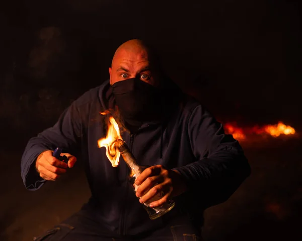 一个戴面具的人拿着一个燃烧的瓶子 自制燃烧弹 — 图库照片
