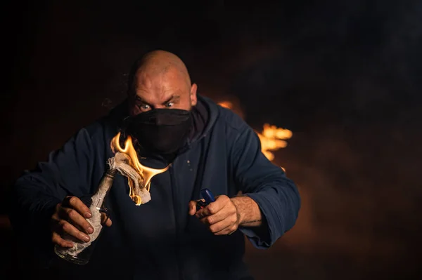 仮面の男が燃えるビンを持っている モロトフカクテル — ストック写真