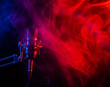 Siyah arka planda pembe dumanlı profesyonel mikrofon.