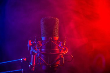 Siyah arka planda pembe dumanlı profesyonel mikrofon.