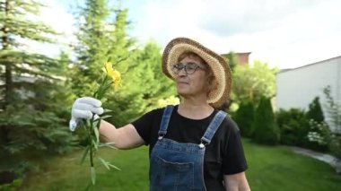 Video 360 derece. Yaşlı beyaz kadın çiftçi elinde çiçek tutuyor.