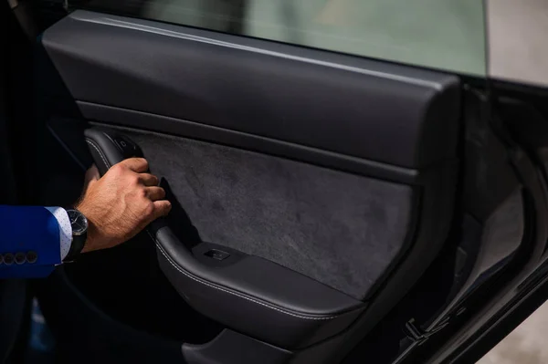 青いスーツの男が車のドアを開ける 高価な時計を手にした男のクローズアップ — ストック写真