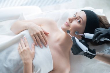 Genç beyaz kadın mikro akım terapi prosedürü uyguluyor. Güzellik bürosu