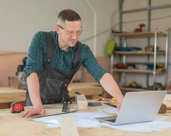 stock image Portrait of a carpenter in a plaid shirt working on a plan in a workshop