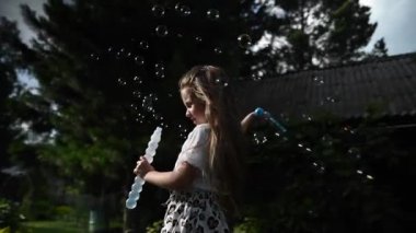 Küçük kız dışarıda sabun köpüğüyle oynuyor. Video 360 derece. Yavaş çekim