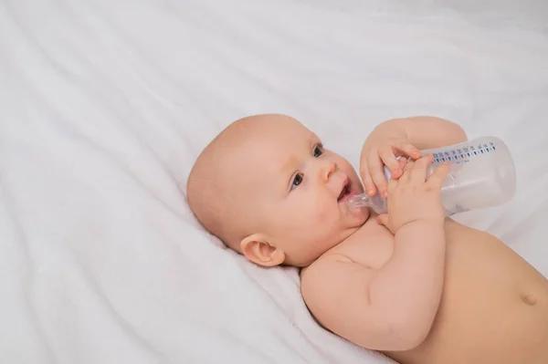 stock image Baby boy chewing on an empty feeding bottle