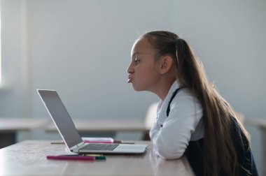 Kafkasyalı kız, okul masasında otururken dizüstü bilgisayarla iletişim kuruyor.