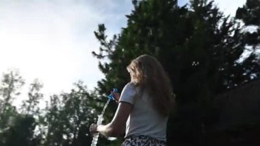 Mutlu beyaz kadın doğada sabun köpüğü üflüyor. Video 360 derece