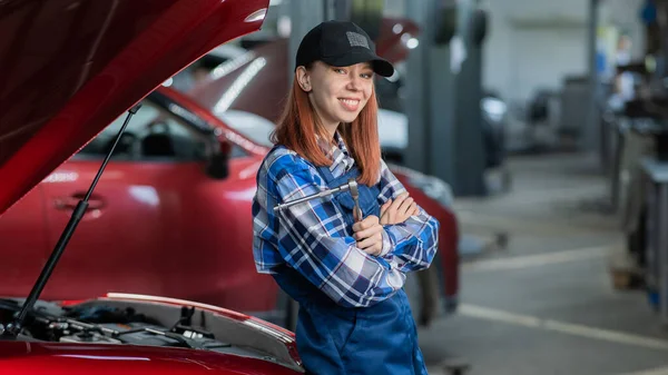 Kadın Bir Oto Tamircisi Arabanın Açık Kaputunda Duruyor Elinde Bir — Stok fotoğraf