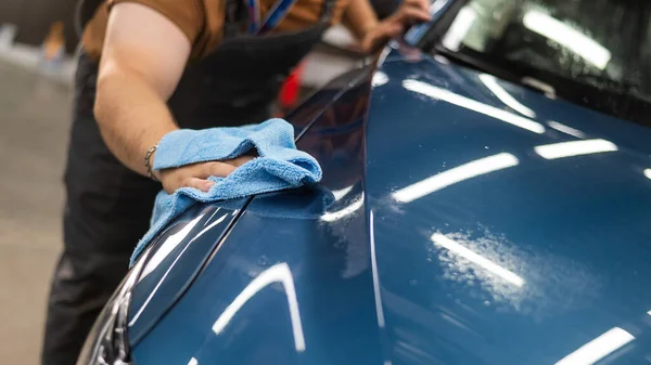 車のサービスのマスターは保護防具フィルムを適用した後ナプキンで車を拭く — ストック写真