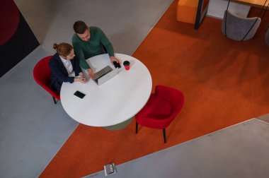 Yuvarlak masada dizüstü bilgisayarla çalışan kadın ve erkeğin üst görüntüsü