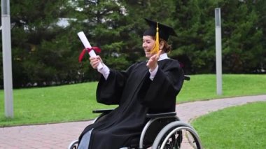 Tekerlekli sandalyedeki beyaz kadın diploma aldığına seviniyor.