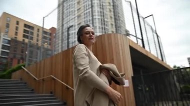 Yaşlı beyaz iş kadını dışarıda ceketini çıkartıyor. Video 360 derece. Yavaş çekim