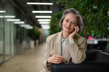 Attractive mature woman sitting on sofa in lobby