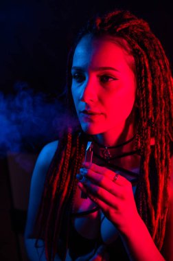 Rastalı beyaz kız kırmızı ışıkta sigara içiyor.