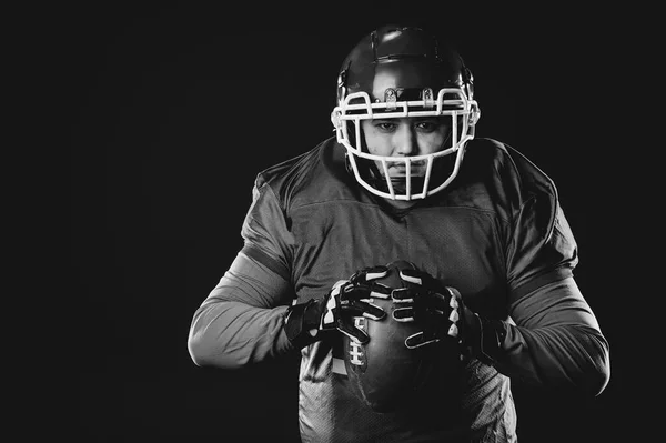 Portrait of a man in uniform for american football on a black background. Monochrome